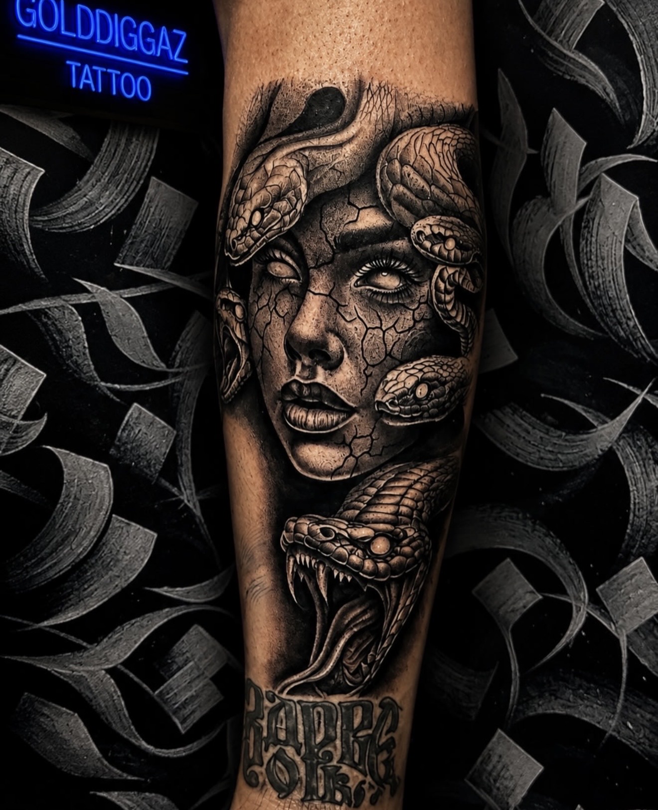 Medusa mit Schlangen in Black and Grey auf dem Unterschenkel, darunter Lettering
