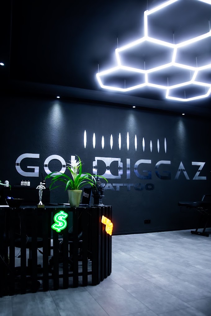 Studio innen: schwarze Wand mit metallischem GOLDDIGGAZ-Schriftzug, darüber die weißen Hexagon-Deckenleuchten